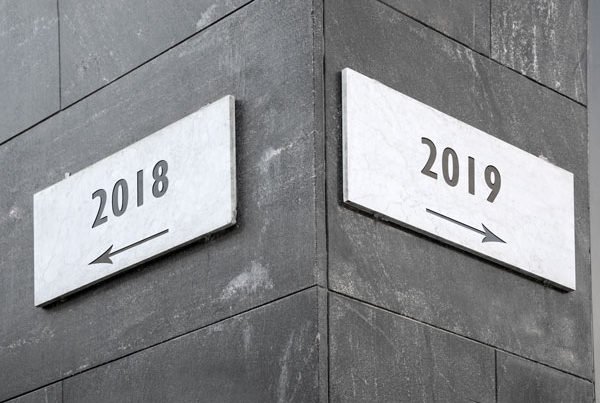 Street signs one stating 2018 and pointing left, the other stating 2019 and pointing right