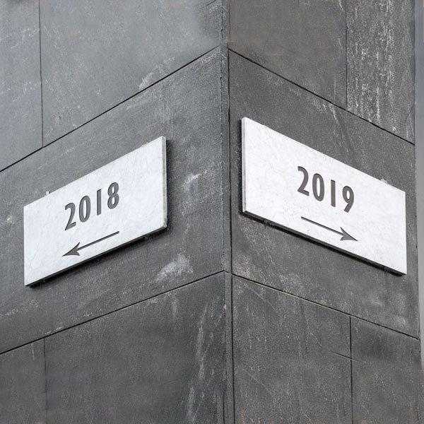 Street signs one stating 2018 and pointing left, the other stating 2019 and pointing right