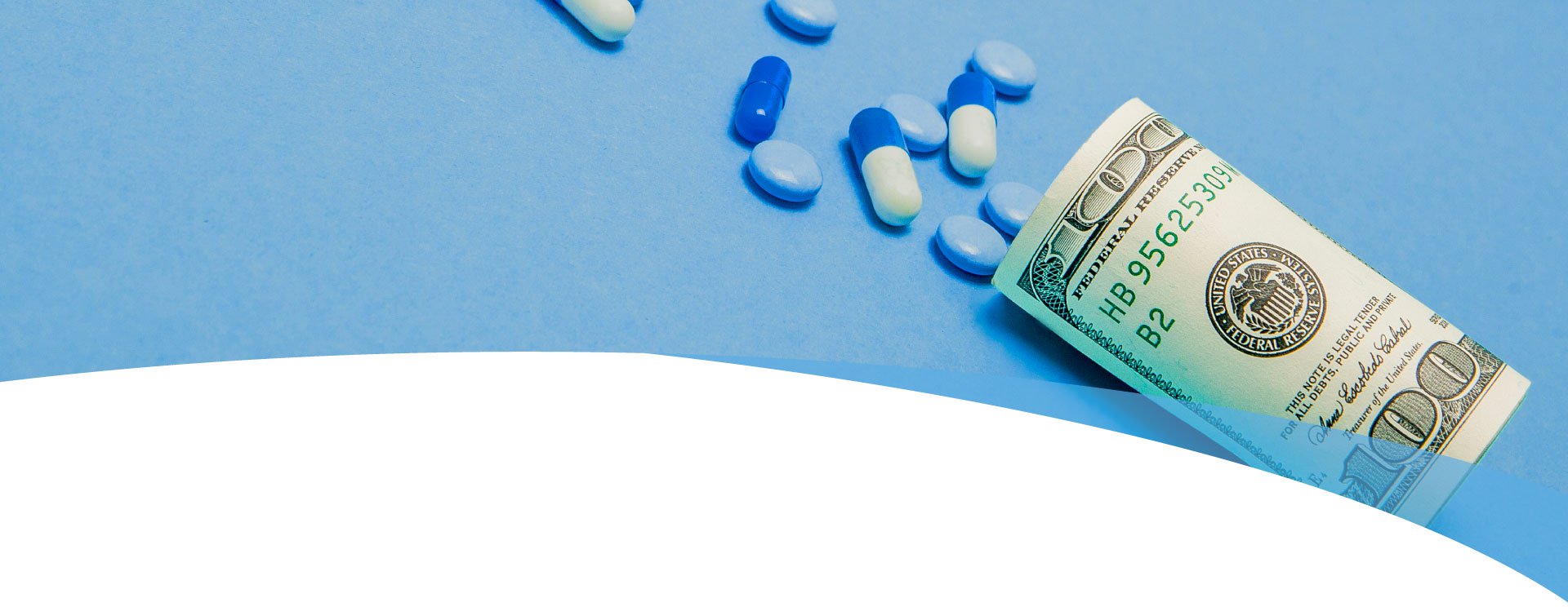 Money rolled up with pills flowing out isolated on blue background, high costs of expensive medication concept.