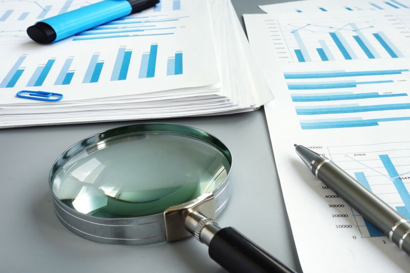 Magnifying glass with bar graphs on papers